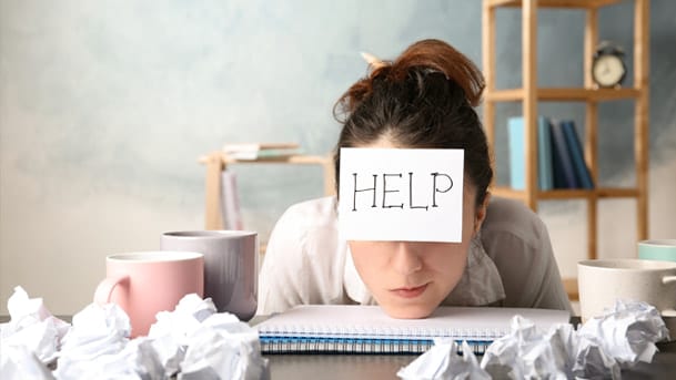 La procrastination est imagée par une jeune femme posant sa tête sur une table de bureau. Son visage est masqué par le mot : "HELP".