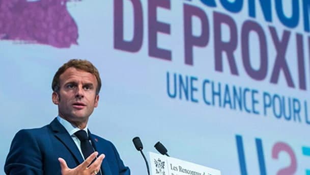 Le président français, Emmanuel Macron est derrière un pupitre à la tribune de "L'Économie de Proximité". Il s'exprime devant une audience.