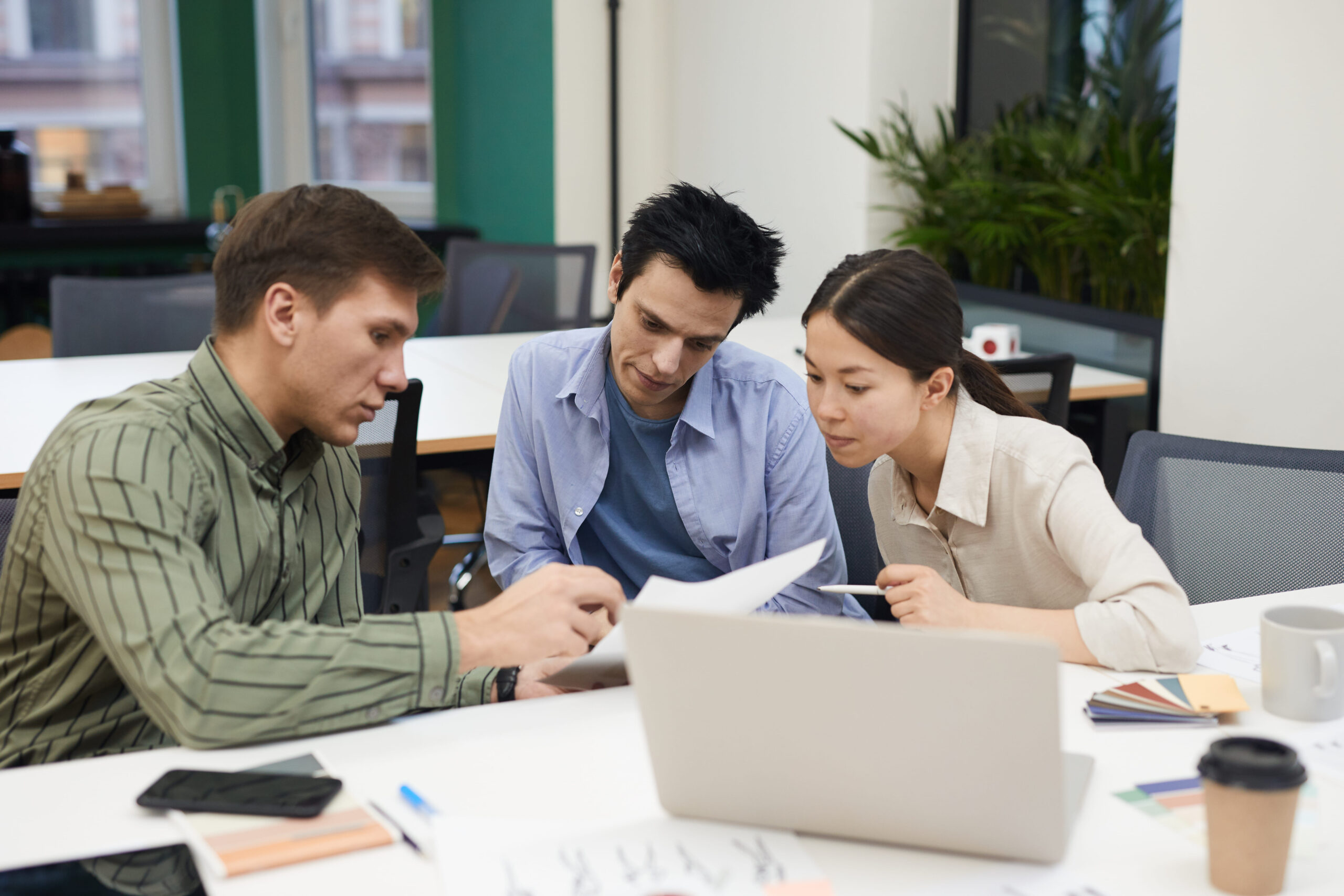 Discussion sur le cumul du portage salarial avec le chômage et la retraite, trois collègues analysant des documents pour présenter des informations clés